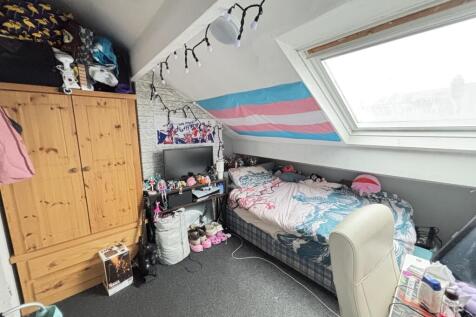 A cozy bedroom with a sloped ceiling and a skyl...