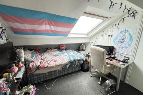 A cozy single bedroom with natural light from a...