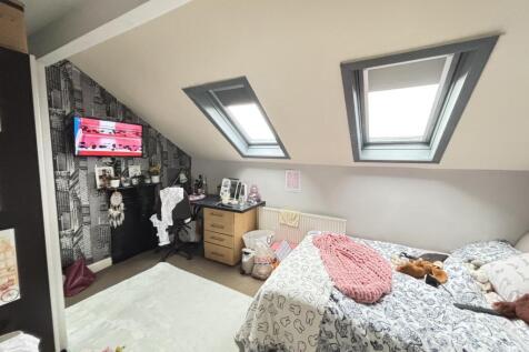 A bright and cozy bedroom with two skylight win...