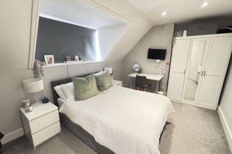 A bright and tidy bedroom featuring a large dou...