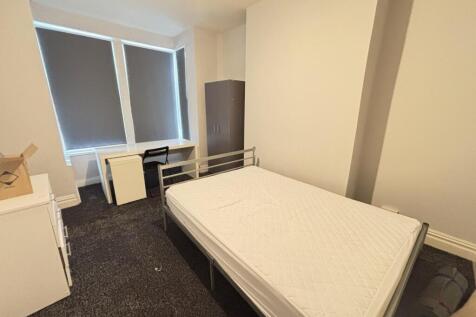 A simple, clean single bedroom with a window pr...