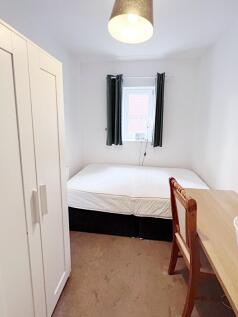 Bright, simply furnished bedroom with a double ...
