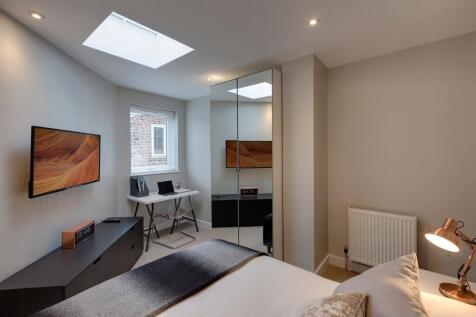 A modern, well-lit bedroom featuring a comforta...