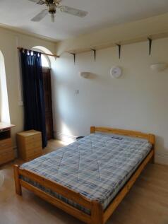 A cozy single bedroom featuring a wooden bed fr...