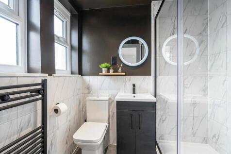 Modern bathroom featuring white marble tiles, a...