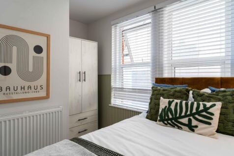 A cozy, well-lit bedroom featuring a comfortabl...