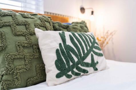 A cozy bedroom with plush, textured green pillo...