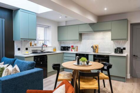 Modern kitchen with sleek green cabinetry, a co...