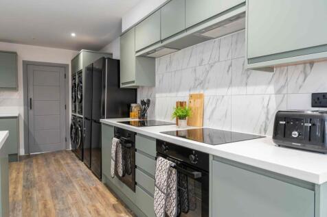 Modern kitchen with sleek green cabinetry, a wh...