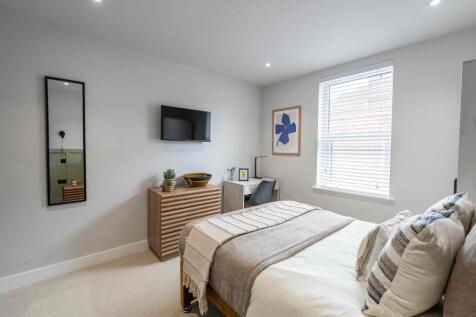 A bright, modern master bedroom featuring a nea...