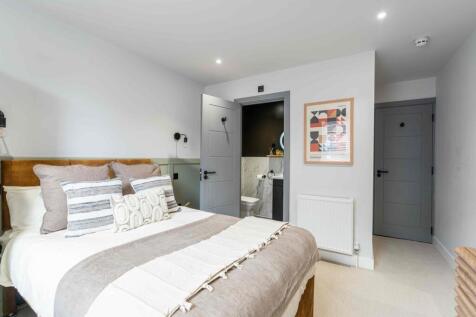 A spacious, well-lit bedroom featuring neatly m...