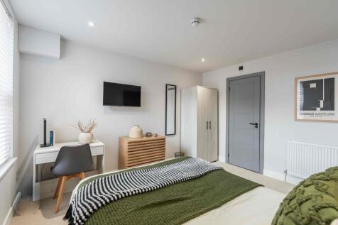 A modern, clean bedroom featuring a comfortable...