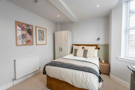 A bright and modern bedroom featuring a comfy b...