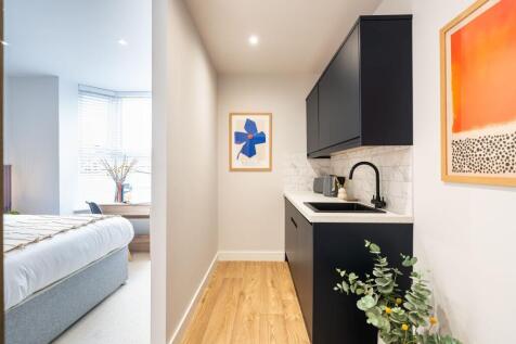A modern, compact kitchen area with sleek black...