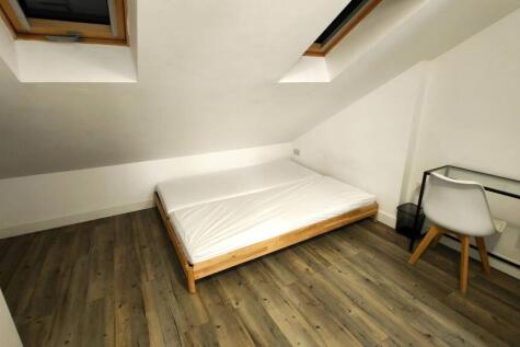 A cozy student&#39;s bedroom featuring a single bed...
