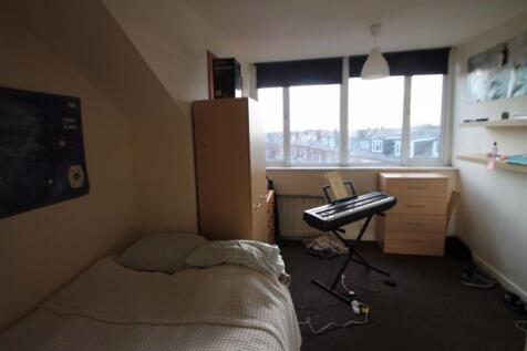 A well-lit bedroom with a single bed, a window ...