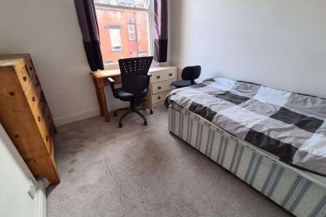 A cozy furnished bedroom featuring a bed, a des...