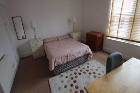 A spacious double bedroom featuring a large bed...