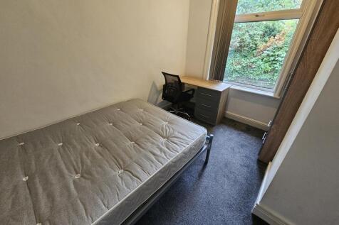 A cozy single bedroom with a comfortable bed po...