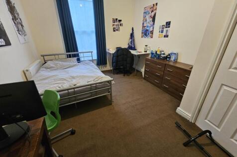 A cozy student bedroom featuring a single bed, ...