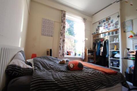 A cozy bedroom featuring a bed with striped bed...