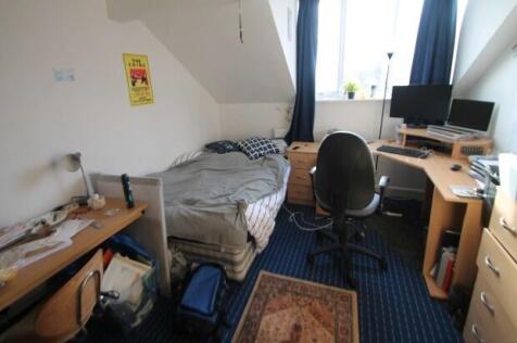 A cozy bedroom featuring a single bed, a desk w...