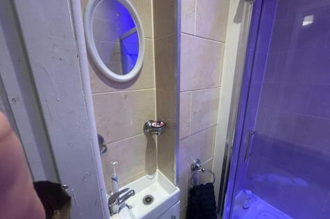 A compact bathroom featuring a small sink, mirr...