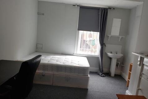 A cozy single bedroom featuring a neatly made b...