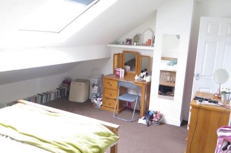 A cozy bedroom with a bed, bookshelf, and perso...