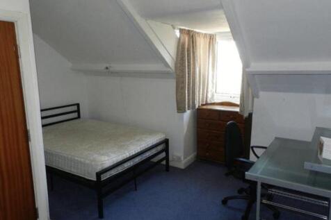 A cozy single bedroom featuring a bed, window w...