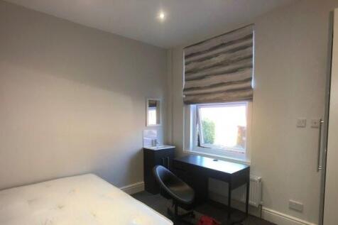 A tidy bedroom with a large window offering goo...