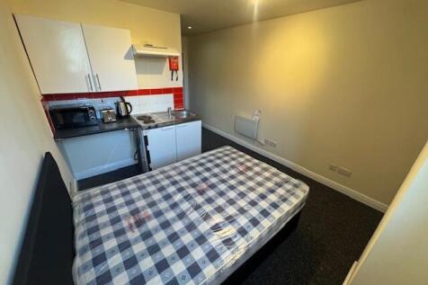 A compact studio apartment featuring a bed with...