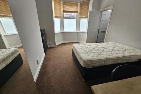 A spacious bedroom with a large window allowing...