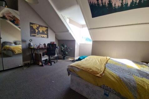 A well-lit bedroom featuring a comfortable doub...