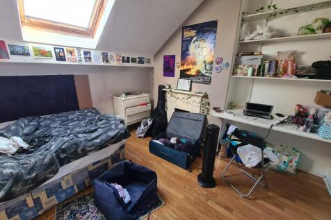 A well-lit bedroom featuring a single bed, work...
