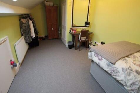 A well-lit, tidy bedroom featuring a comfortabl...