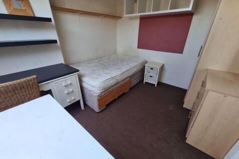 A cozy student bedroom featuring a single bed, ...