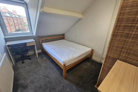 A cozy single bedroom featuring a comfortable b...