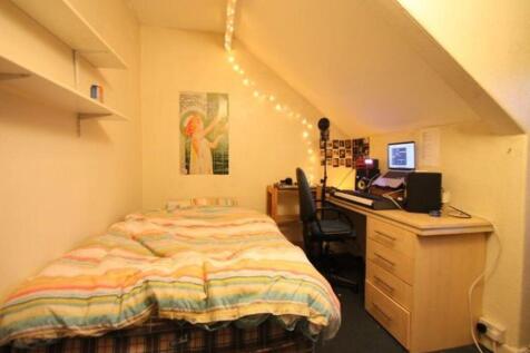 A cozy bedroom with a neatly made bed featuring...