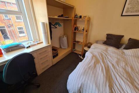 A cozy single bedroom with a neatly made bed, a...