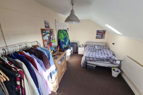 A well-lit bedroom with a neatly made bed, ampl...