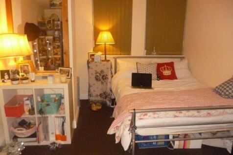 A cozy bedroom with a neatly made bed, bedside ...