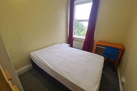 A cozy bedroom featuring a single bed positione...