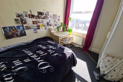 A cozy bedroom featuring a neatly made bed with...