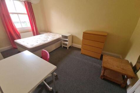 A cozy bedroom featuring a single bed, a small ...