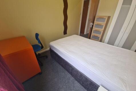 A cozy single bedroom featuring a comfortable b...