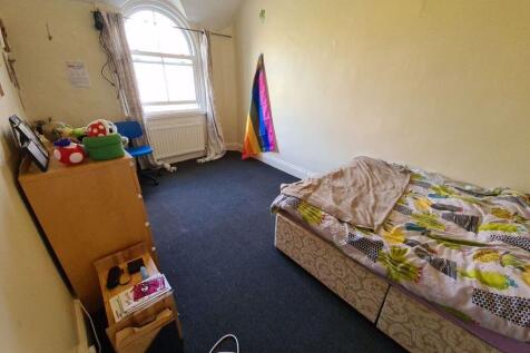 A modest bedroom featuring a single bed with a ...