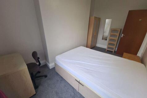 A simple single bedroom with basic furnishings ...