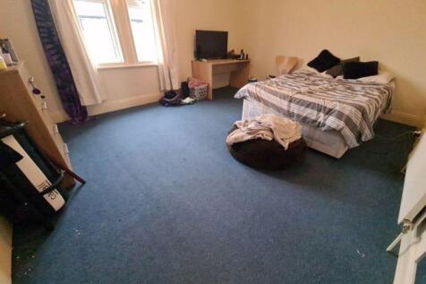 A spacious double bedroom with a neatly made be...
