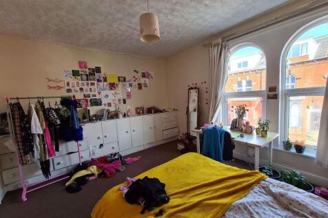 A cozy bedroom featuring a neatly made bed, nat...